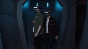 Young men walking along a corridor while using AR technology. Skilled gamers in virtual reality headsets playing online tournament together. High quality 4k footage