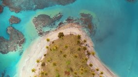 Aerial view of tropical paradise island in the ocean with palm beach. Vibrant tropical nature. Turquoise sea waves on golden sand. The concept of summer holidays and tropical beach. Video is toned.