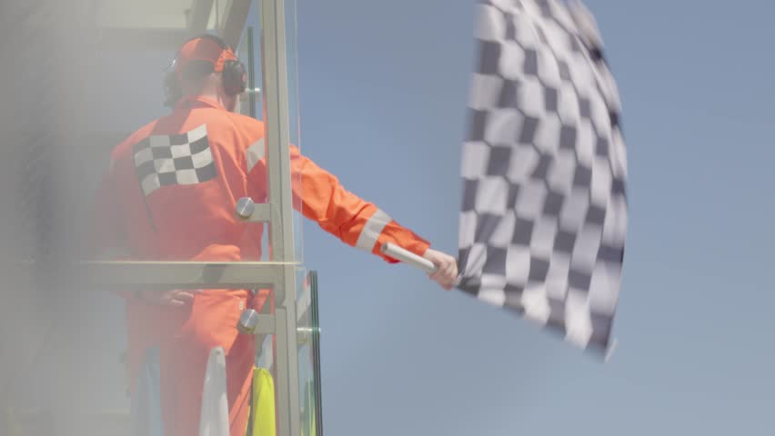 Man holding and waving Checkered race at finish line on a raceway. Victory, achievement, success and sport concept.  Royalty-Free Stock Footage #1103020533
