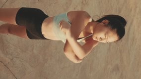VERTICAL VIDEO, girl in sports top does workout, stretching and gymnastics at morning time on modern buildings background