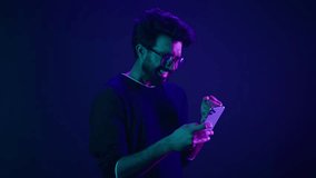 Indian man Arabian male model guy win mobile phone success victory smartphone achievement winning game cellphone internet betting online money prize at ultraviolet neon dark blue studio background - Powered by Shutterstock - Get 15% off with code: PIKWIZARD15