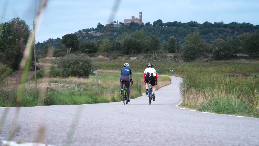 4K footage of two people ciclying a countryside road in Catalonia, Spain.
Mid angle, no movement.