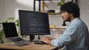 Young Hindus programmer works on computer sitting at desk in cozy apartment. Proficient male with kinky hair types and corrects data carefully - Powered by Shutterstock - Get 15% off with code: PIKWIZARD15
