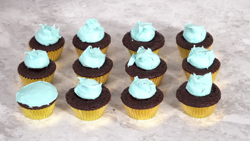 Decorating chocolate cupcakes with buttercream frosting and rainbow candy.
