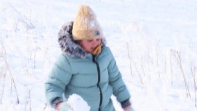Video shoot of close up little girl in blue warm jacket and hat walking on knees, making snow footpath with legs and arms, playing in snow. Innocent joy snowy weather, winter fun and leisure activity