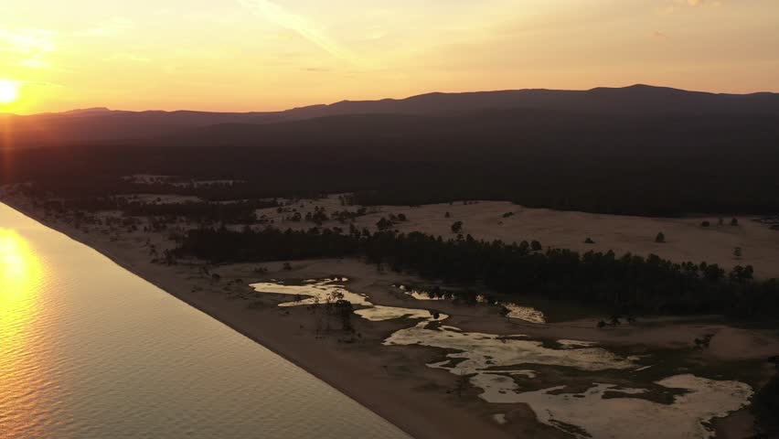 The first rays of the rising sun on the shore. Lake Baikal. Siberia, Russia.