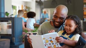Father and daughter reading book at home together with multi-generation family in background - shot in slow motion - Powered by Shutterstock - Get 15% off with code: PIKWIZARD15