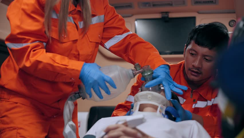 Asian emergency medical technician (EMT) or paramedic giving emergency oxygen with patient in ambulance car Royalty-Free Stock Footage #1103042183