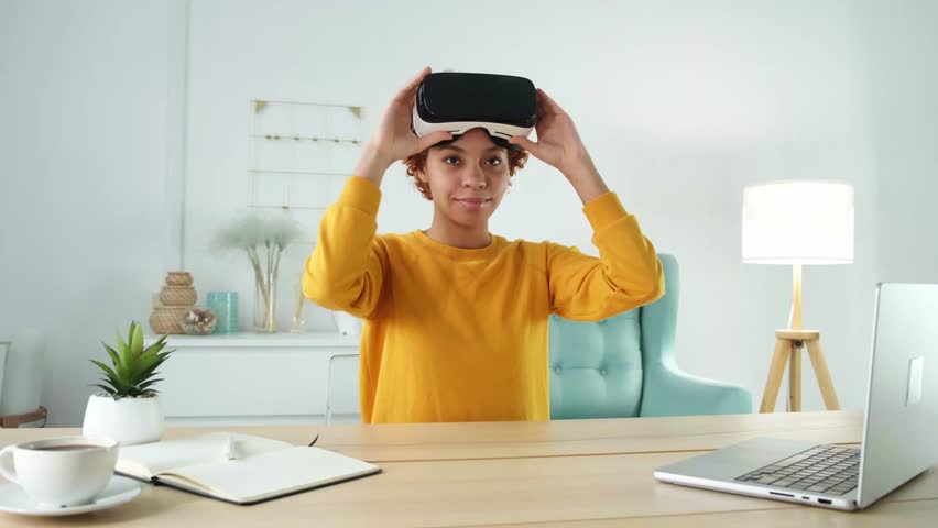 African american young woman wearing using virtual reality metaverse VR glasses headset at home. Girl puts on virtual reality helmet. Technology simulation hi-tech videogame concept Royalty-Free Stock Footage #1103048189