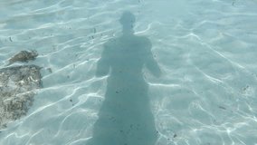 View of the shadow of a man reflected on the seabed in slow-motion.