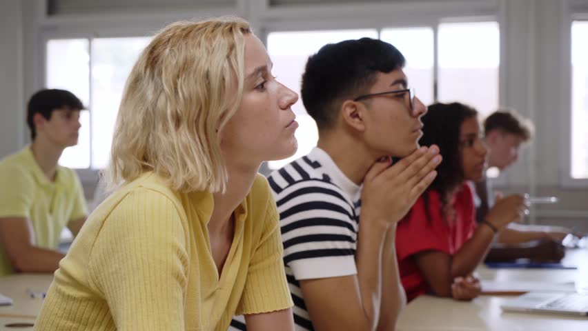 Young people in history and philosophy class in high school. Focus on girl raises her hand and asks the teacher a question as she attends. Group of students learning in classroom.  Royalty-Free Stock Footage #1103052937