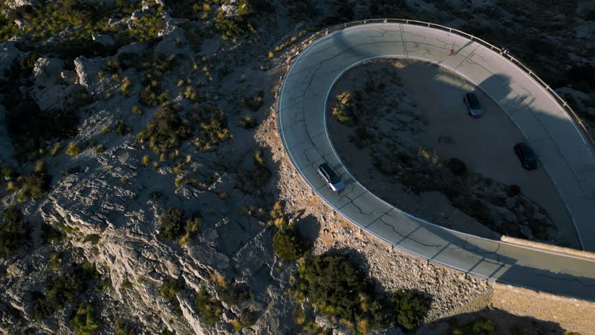 Modern car driving at Hairpin Bend at Sa Calobra, Palma de Mallorca. Serpentine road in the mountains. Scenic epic Majorca Island nature aerial drone footage. Famous for racing bikes. Cinematic 4K UHD