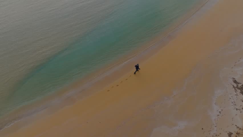 Person walking along Cala Pregonda beach in Menorca, Spain at low tide making footsteps.