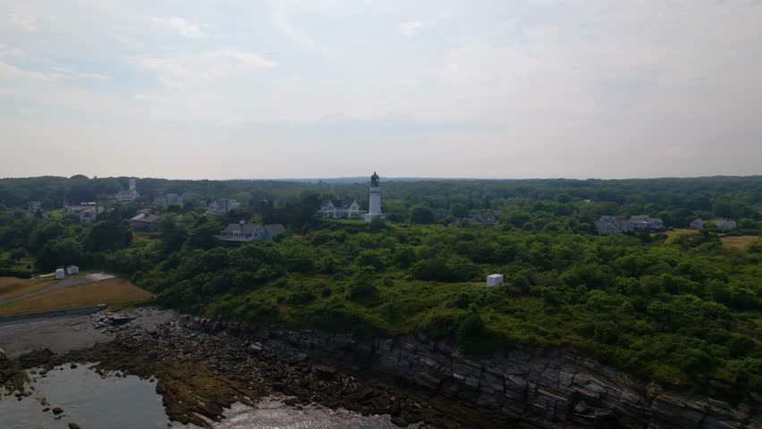 Cape Elizabeth Lighthouse rotating frame. Lighthouse on the coast in southern Maine amid seaside shrubbery and rocky bluffs on a warm Summer day