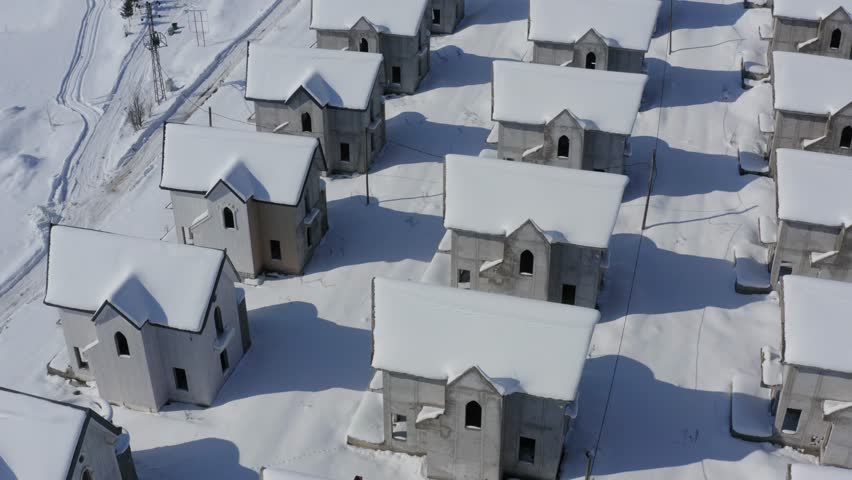 Drone flying low down between building project of identical homes covered in snow Royalty-Free Stock Footage #1103056559