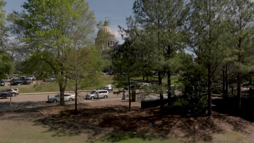 Mississippi State Capitol building in Jackson, Mississippi with drone video moving up from street level.