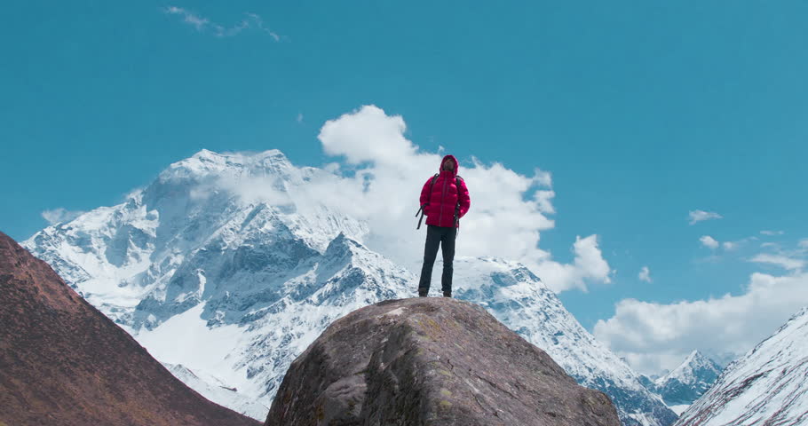 A mesmerizing orbit view of a man in a red jacket, shot by Drone, enjoying the stunning views of the huge Himalayan mountains and clouds during the Manaslu Circuit trek in Nepal. Royalty-Free Stock Footage #1103056785