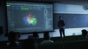 Young University Professor Explaining the Importance of Artificial Intelligence to a Group of Diverse Multiethnic Students in a Dark Auditorium. Teacher Showing Big Data Ecosystem on Two Big Screens - Powered by Shutterstock - Get 15% off with code: PIKWIZARD15