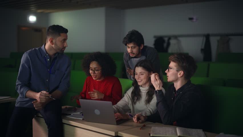 Diverse Happy Students Having a Conversation with a Teacher in University Classroom, Working on a Shared Research Project on a Laptop Computer. Classmates Working Together on College Science Project Royalty-Free Stock Footage #1103066915