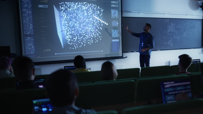 Young University Professor Explaining the Importance of Artificial Intelligence to a Group of Diverse Multiethnic Students in a Dark Auditorium. Teacher Showing Neural Network on Two Big Screens Royalty-Free Stock Footage #1103067021