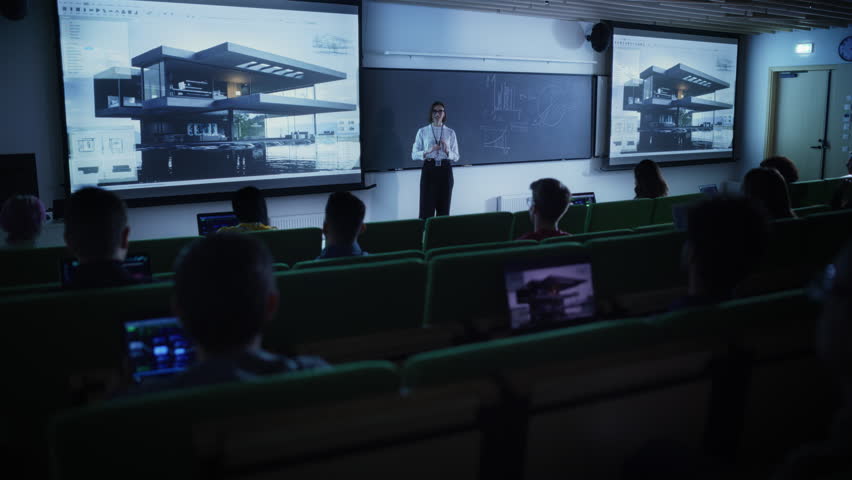 Young University Professor Explaining the Principles of Modern Architecture to a Group of Diverse Multiethnic Students in a Dark Auditorium. Female Teacher Showing a Housing Project on Two Big Screens