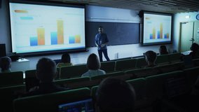 Young Male Teacher Giving a Business Strategy Lecture to Diverse Multiethnic Group of Female and Male Students in Dark College Room. Projecting Slideshow with Comparison Charts and Commercial Data - Powered by Shutterstock - Get 15% off with code: PIKWIZARD15