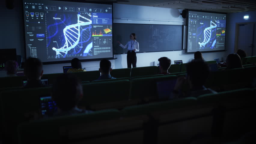 Young University Professor Explaining a DNA Sequencing Methods to a Group of Diverse Multiethnic Students in a Dark Auditorium. Female Teacher Showing a Macro Image of a DNA Structure on a Big Screen Royalty-Free Stock Footage #1103067059
