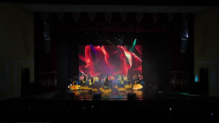 A collective of musicians, singers and dancers in gypsy costumes perform on stage.