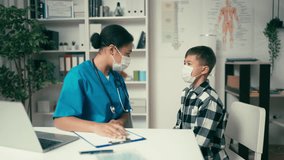 Pediatrician in protective mask talking to boy in her office, children's health - Powered by Shutterstock - Get 15% off with code: PIKWIZARD15