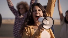 At protest, woman shouts with megaphone raising her fist in crowd. People demonstrating for their rights. High quality FullHD footage - Powered by Shutterstock - Get 15% off with code: PIKWIZARD15