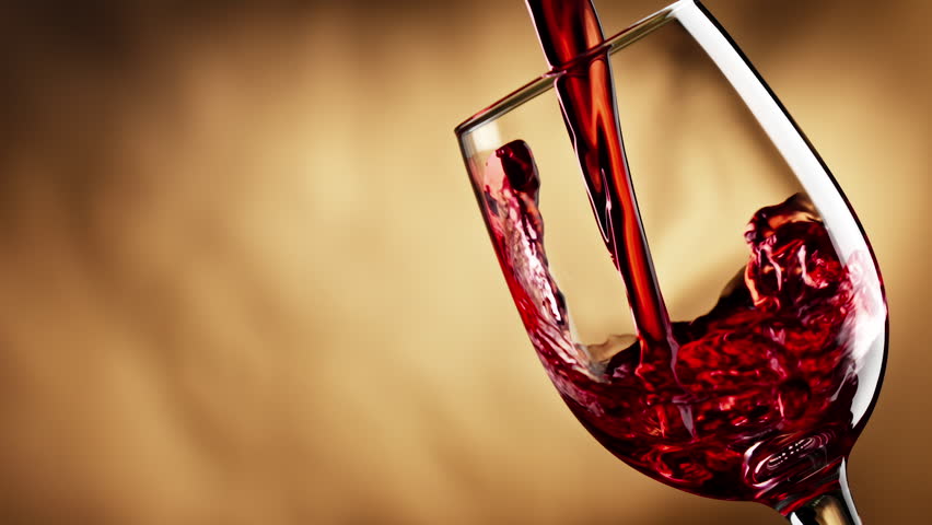 Red wine forms beautiful wave. Wine pouring in wine glass over yellow background. Slow motion of pouring red wine from bottle into goblet. Alcohol concept with copy space