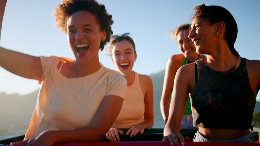 Portrait of female friends standing up through sunroof of car laughing on road trip through countryside with friends - shot in slow motion Royalty-Free Stock Footage #1103072251