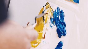Vertical video. Artwork creation. Female artist. Interior picture. Unrecognizable woman painting abstract landscape on board canvas with spatula colorful paints.