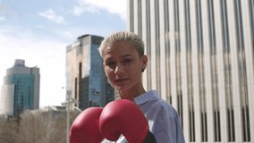 Businesswoman throwing punches wearing red boxing gloves outdoors - Powered by Shutterstock - Get 15% off with code: PIKWIZARD15