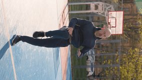 A bald man in a sportswear is exercising on a sports playground. The amateur athlete is doing high knees running in place. Vertical video