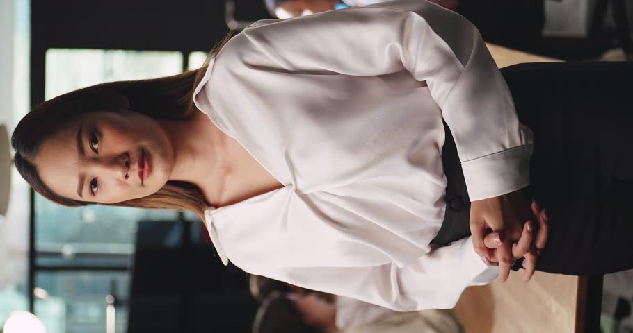 Vertical clip. Portrait of young beautiful businesswoman standing with arms crossed looking at camera in office.