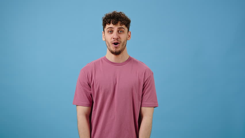 Caucasian cheerful handsome young man applauding and pointing fingers, making double thumbs up gesture on blue isolated background. Amazed male clapping hands looking at camera Royalty-Free Stock Footage #1103083627