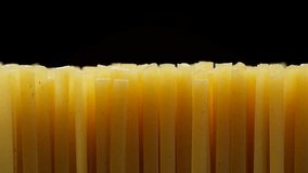 Raw spaghetti isolated on black background, slider shot. Traditional Italian pasta