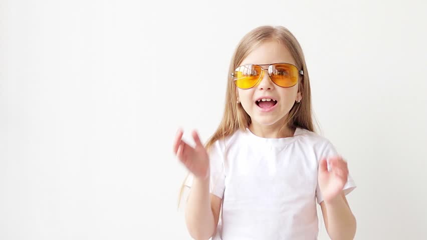 Beautiful young girl in fashionable glasses on a white background shows emotions