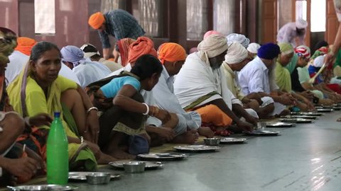 AMRITSAR, INDIA - SEPTEMBER 29, 2014:  Unidentified poor indian people receive a free meal inside the 'langar', a communal kitchen on the famous Sikh Golden Temple complex in Amritsar.