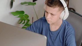 Teen boy watches funny video or movie on computer at home. Home entertainment.