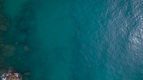 Drone slow top view of a rocky cliff and blue water waves of the Mediterranean Sea, Spain