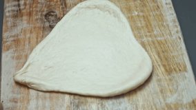 Contour effect of Rolling out fresh dough for pizza on wooden cutting board. Preparing heart shaped pizza for Valentine's Day for a loved one. 4K video. Artistic shooting