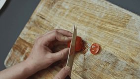 Contour effect of Slicing red cherry tomatoes with kitchen knife on wooden board, Preparing heart shaped pizza for Valentine's Day for a loved one. 4K video