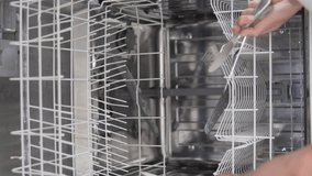 A woman puts dirty dishes in the dishwasher at home. Vertical video