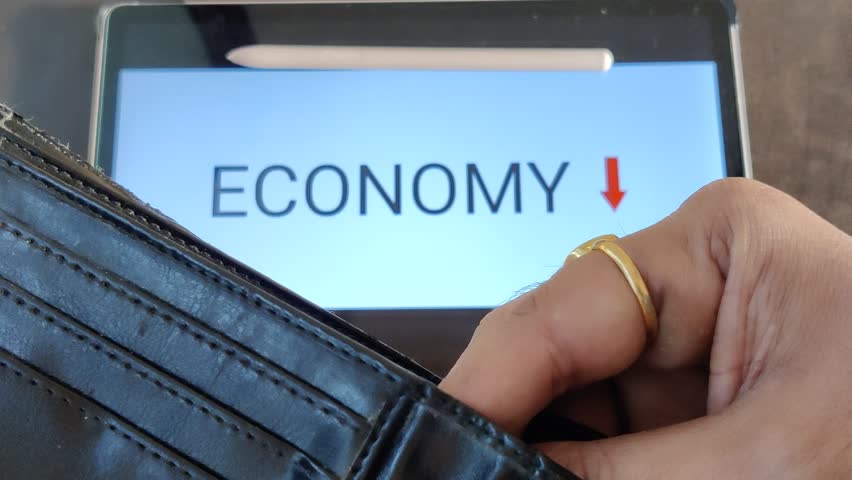 Footage of a person taking out money from his wallet. ECONOMY with a downward pointing arrow is written in background. Footage is depicting economic fall. Royalty-Free Stock Footage #1103118615