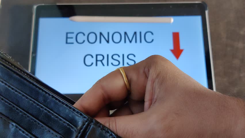 Footage of a person taking out money from his wallet. ECONOMIC CRISIS with a downward pointing arrow is written in background. Footage is depicting economic fall. Royalty-Free Stock Footage #1103118637