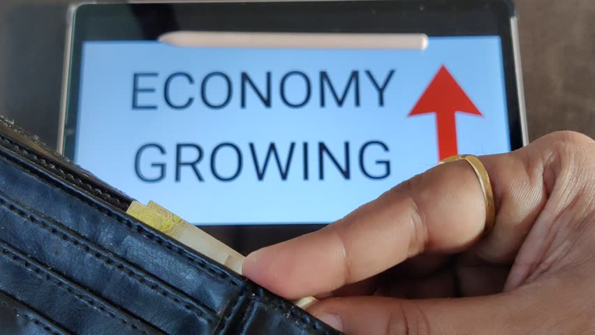Footage of a person taking out money from his wallet. ECONOMY GROWING with an upward pointing arrow is written in background. Footage is depicting economic growth. Royalty-Free Stock Footage #1103119001