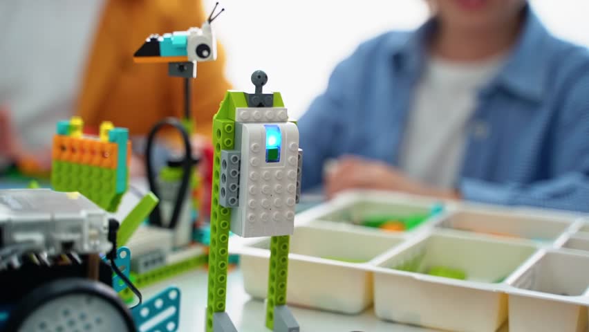 Robotics programming class. Children construct and code Robot. STEM education using constructor blocks and laptop tablet, remote control joystick. Technology educational development for school kids. 