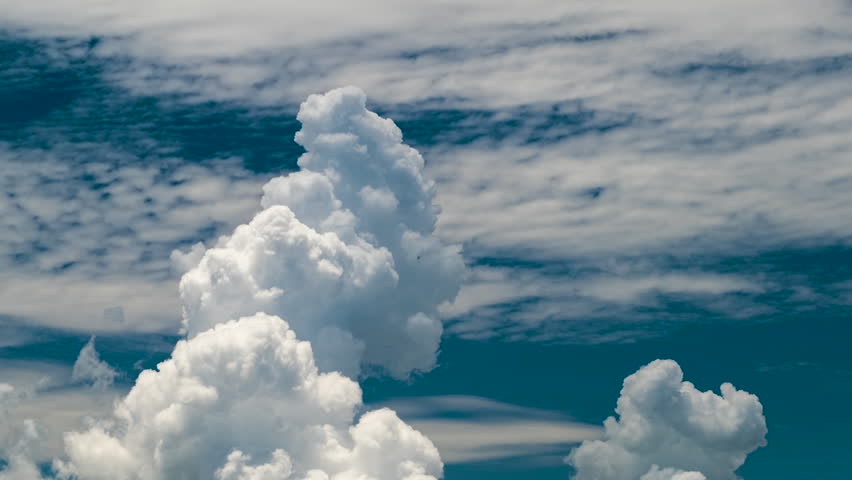 Timelapse of white puffy cumulus clouds forming on summer blue sky. Moving and changing cloudscape weather